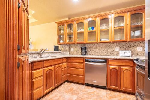 a kitchen with wooden cabinets and a stainless steel dishwasher at Lighthouse Beach Villas in San Pedro