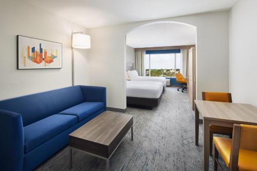 Habitación de hotel con sofá azul y cama en Holiday Inn Express Hotel & Suites Port St. Lucie West, an IHG Hotel en Port Saint Lucie