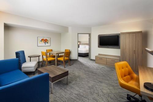 a hotel room with a living area with a table and chairs at Holiday Inn Express Hotel & Suites Port St. Lucie West by IHG in Port Saint Lucie