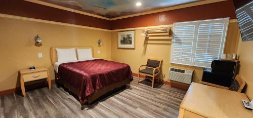 a bedroom with a bed and a desk and a window at Geneva Motel in Inglewood