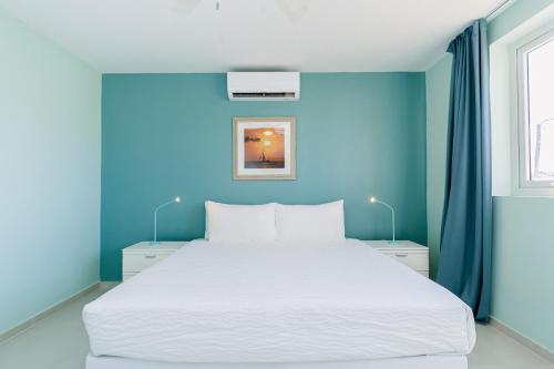 Un dormitorio con una gran cama blanca con paredes azules. en Turibana 50 G, en Noord