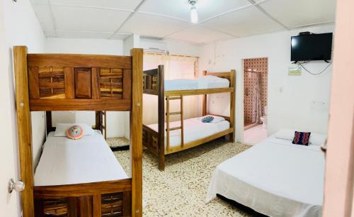 Pokój z 3 łóżkami piętrowymi i telewizorem w obiekcie Hostal Liwa Kashi w mieście Ríohacha