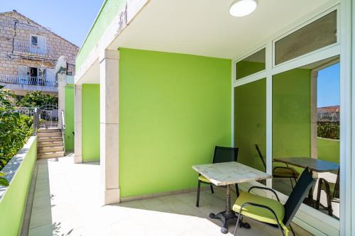 a patio with a table and chairs on a green wall at Green Paradise in Mlini