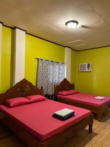 two beds in a room with green and yellow walls at Vhauschild Transient Rooms -B in Alaminos