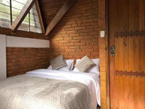 a bed in a room with a wooden wall at Mountain Chalet - Tungurahua Hot Springs/Aguas Termales in Baños