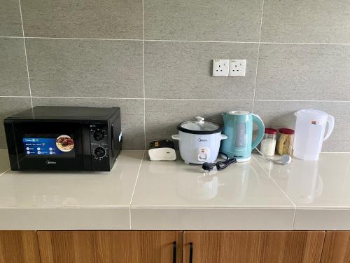 a kitchen counter with a microwave and some cups at Homestay Myya in Beris Tok Saboh