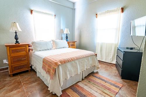 a bedroom with a bed and a dresser and two windows at Lighthouse Beach Villas in San Pedro