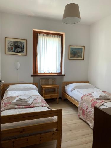 1 dormitorio con 2 camas y ventana en Residence Alpen Casavacanze, en Pinzolo