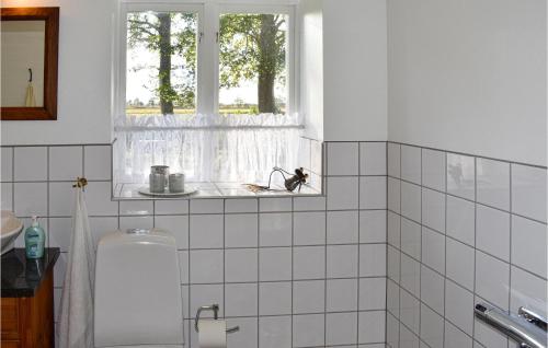 a white tiled bathroom with a window and a sink at Stunning Home In Vollsj With 3 Bedrooms And Wifi in Vollsjö