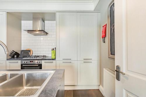 a kitchen with white cabinets and a sink at Pier View in Weston-super-Mare