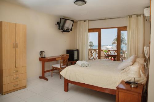 a bedroom with a bed and a desk and a television at Hotel Emancipador in Paracas