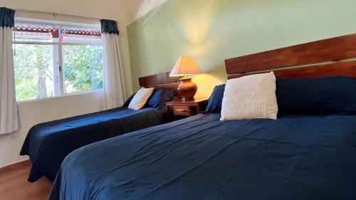 a bedroom with two beds and a lamp and a window at Lourdes Hotel Campestre in Tierranueva