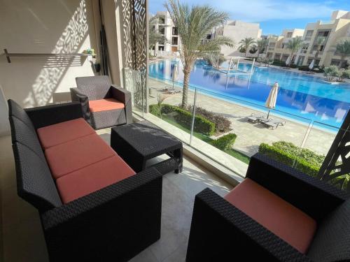 a balcony with two chairs and a large pool at Lovely 2-bedroom apartment with pool view in Hurghada
