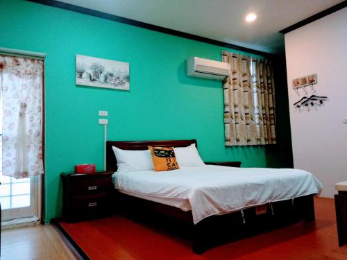 zieloną sypialnię z łóżkiem i zieloną ścianą w obiekcie Ju Jia Xiao Zhan Homestay w mieście Guanshan
