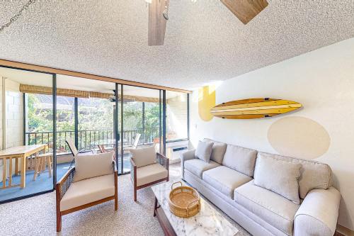 a living room with a couch and a surfboard on the wall at Kalanikai #112 in Kailua-Kona
