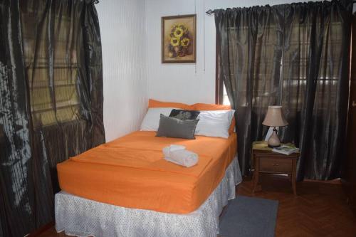 a bedroom with a bed with an orange comforter at Maggie's Guest House/10 Min Walk to City- Certified in Branns Hamlet