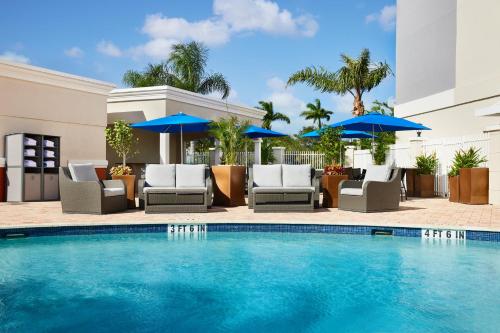 a pool at a hotel with chairs and umbrellas at Holiday Inn Express Hotel & Suites Port St. Lucie West by IHG in Port Saint Lucie