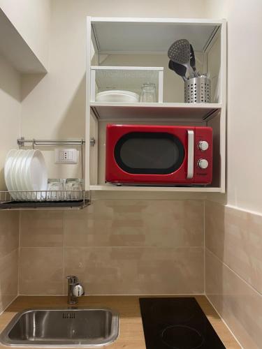 un forno a microonde rosso in una cucina con lavandino di La Dimora Dei Sogni a Napoli
