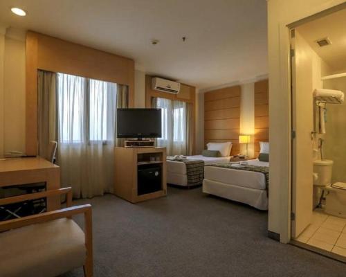 a hotel room with two beds and a flat screen tv at Flat Nobile Congonhas em frente ao aeroporto - H614 in São Paulo