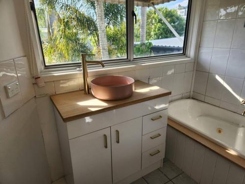 baño con lavabo, bañera y ventana en Classic Brisbane Queenslander with Pool & Yard en Brisbane