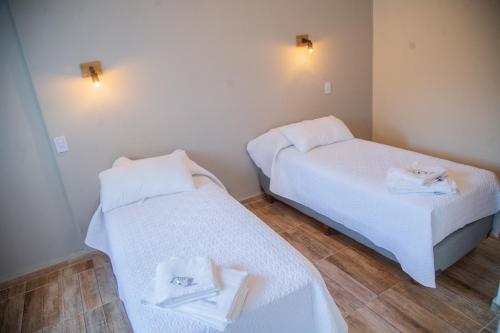 2 bedden in een kamer met witte lakens en handdoeken bij Hotel Anmara in San Juan