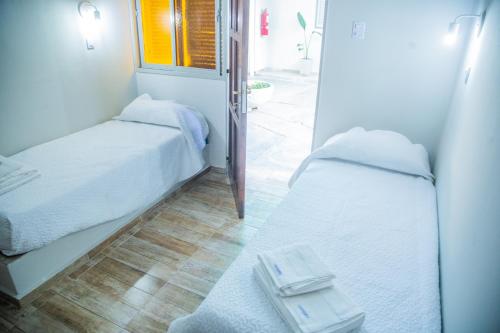 two beds in a small room with a window at Hotel Anmara in San Juan