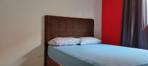 a bed with a brown headboard and two pillows at Hollydayhouse in Prudentópolis