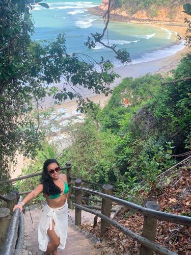 a woman in a white dress standing on a stairway to a beach at Sonia Flats Pipa's Bay - Flat 211 in Pipa