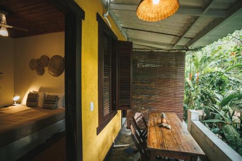 een veranda met een houten tafel en een bed in een kamer bij Pousada Pouso da Maré in Ilha de Boipeba