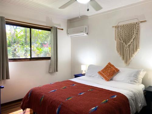 a bedroom with a bed with a red blanket and a window at Casa Colores in Montezuma