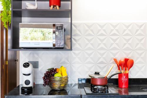 a kitchen counter with a stove and a microwave at Flats Una's Corner - Novos - Ar Condicionado in Barra do Una