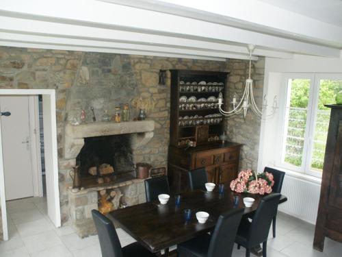 une salle à manger avec une table et une cheminée en pierre dans l'établissement Holiday Home in Brittany near Sandy Beaches, à Saint-Jean-du-Doigt