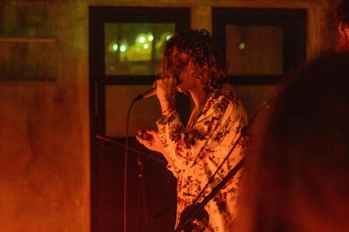 a woman singing into a microphone on a stage at Refugio Surf Lodge in Tamarindo