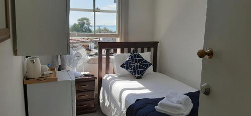 a small bedroom with a bed and a window at The Prospect of Howick Accommodation in Auckland