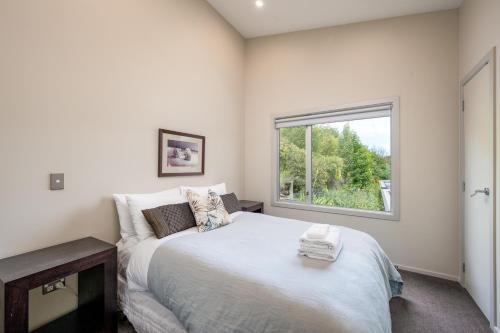 a bedroom with a large white bed and a window at Luxury Lakeview Vista Apartment in Wanaka