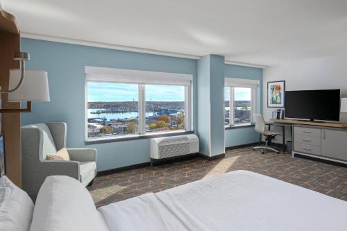 a hotel room with a bed and a desk with a television at Holiday Inn Portland-By the Bay by IHG in Portland