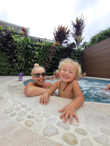 a woman and a little girl laying in a swimming pool at The Oasis Apartments and Treetop Houses in Byron Bay