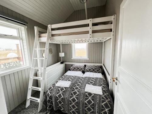 a bunk bed in a small room with a ladder at Garður Apartments in Gardur
