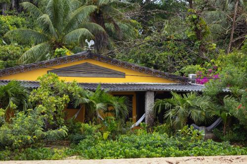 a yellow house in the middle of a garden at Pousada Pouso da Maré in Ilha de Boipeba