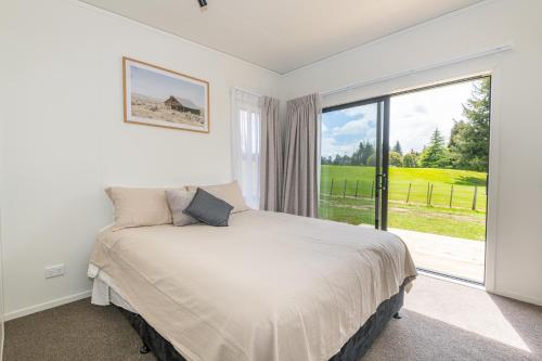 a bedroom with a bed and a large window at Fairway Cottages in Rotorua