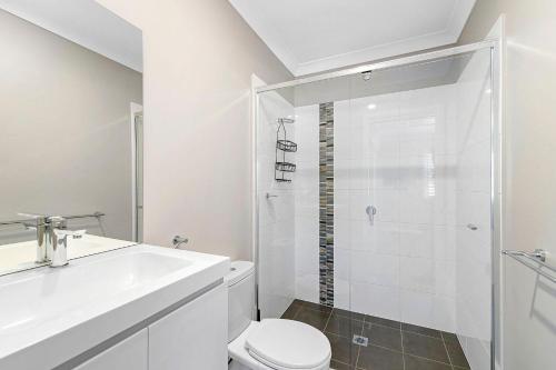a bathroom with a shower and a toilet and a sink at Cathie 29 in Port Macquarie