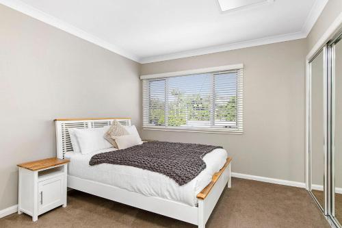 a white bedroom with a bed and a window at Cathie 29 in Port Macquarie
