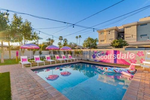 a swimming pool with pink chairs and umbrellas at Scottsdoll Dreamhouse Walk to Old Town NEW in Scottsdale