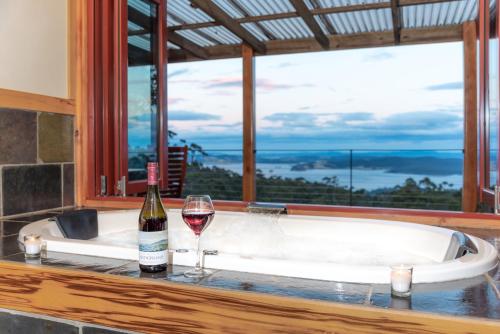 a bath tub with a bottle of wine and a glass at Woodbridge Hill Hideaway in Woodbridge