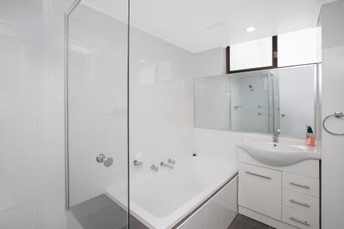 La salle de bains blanche est pourvue d'une douche et d'un lavabo. dans l'établissement Tasman 15, à Port Macquarie