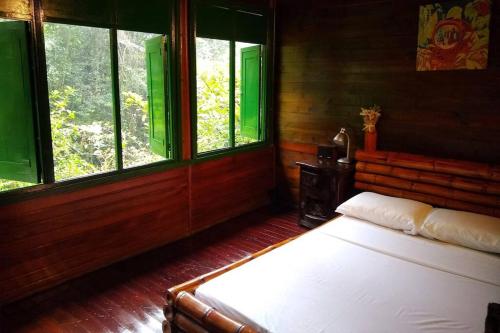 a bedroom with a bed in a room with windows at Chalet a orillas del rio Pance in Cali