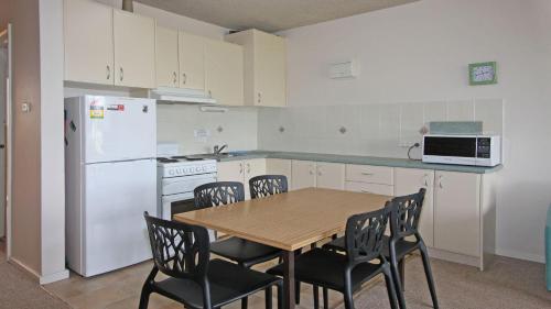 a kitchen with a table and chairs and a white refrigerator at Pacific 2 in Port Macquarie