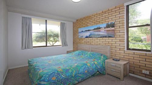 a bedroom with a bed and a brick wall at Pacific 2 in Port Macquarie