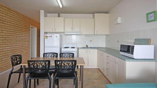 a kitchen with white cabinets and a table and chairs at Pacific 2 in Port Macquarie