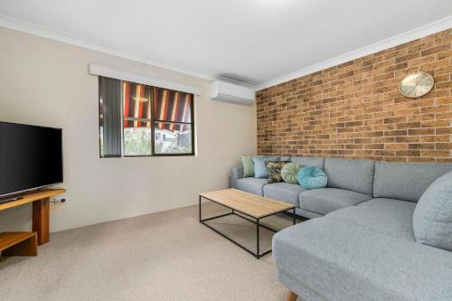 a living room with a couch and a brick wall at Talga 5 in Port Macquarie